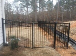 A black aluminum fence with a gate installed along a property line by Fencingphd.nc in Fayetteville, NC.