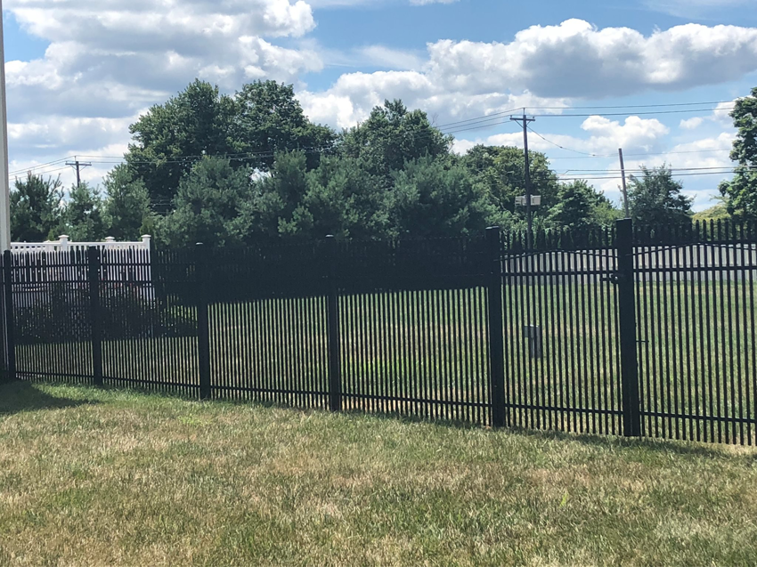 A black aluminum fence with a white privacy fence in the background, installed by Mercer Fence Company in Hamilton Township, NJ.
