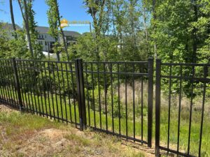 A black aluminum fence installed in a natural wooded area, providing security and definition by Limitless Boundaries LLC in Garner, NC.