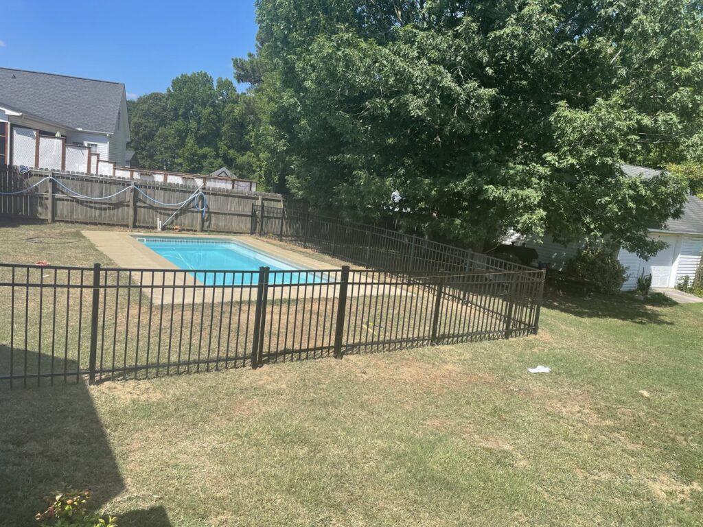 A safety-compliant black aluminum fence installed around a swimming pool by Aguilarfence services LLC in Clayton, NC.