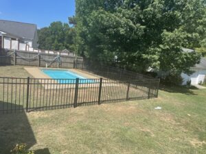 A safety-compliant black aluminum fence installed around a swimming pool by Aguilarfence services LLC in Clayton, NC.