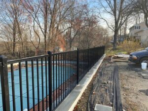A black aluminum fence installed around a pool area during construction by Flanagan Fencing in Brookfield, CT.