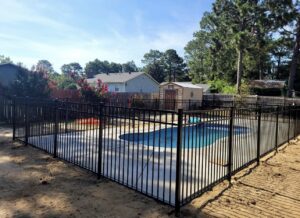 A black aluminum fence installed around a swimming pool for safety by Fencingphd.nc in Fayetteville, NC.