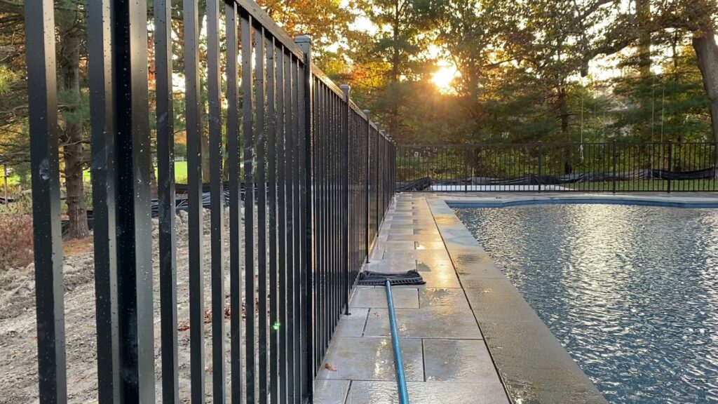 A sleek black aluminum fence installed around a swimming pool by Flanagan Fencing in Brookfield, CT.