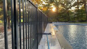 A sleek black aluminum fence installed around a swimming pool by Flanagan Fencing in Brookfield, CT.