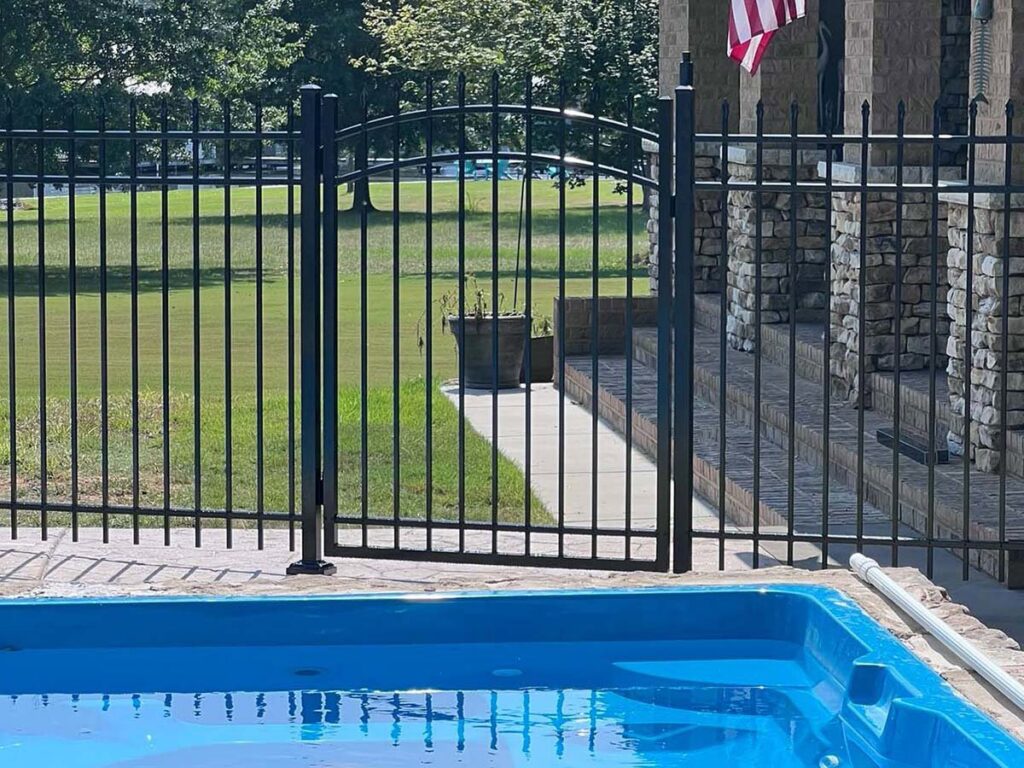 A black aluminum fence with a gate installed around a swimming pool for safety by RUCO Fence in Huntsville, AL.