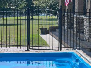 A black aluminum fence with a gate installed around a swimming pool for safety by RUCO Fence in Huntsville, AL.