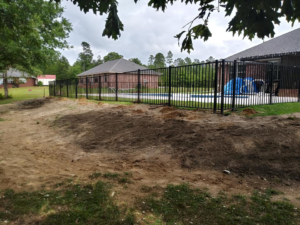 A newly installed black aluminum fence surrounding a swimming pool, completed by Country Boyz fencing in Biloxi, MS.