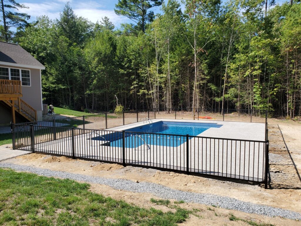 A black aluminum fence installed around a swimming pool for safety by MH Fence in Weare, NH.