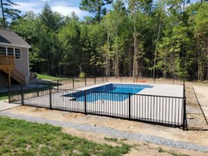 A black aluminum fence installed around a swimming pool for safety by MH Fence in Weare, NH.