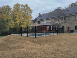 Black aluminum fence installed around a backyard pool next to a house by Wallace Fencing in Cincinnati, OH.