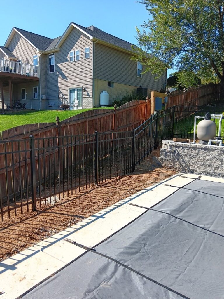 A black aluminum fence installed around a pool area on a sloped property by A Freedom Fence in Martinsburg, WV.