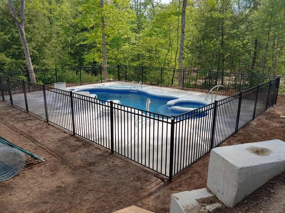A secure black aluminum fence installed around a swimming pool by Precision Fence NH in Hooksett, NH.