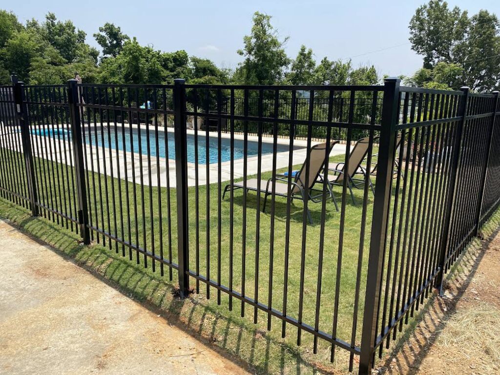 A newly installed black aluminum fence providing safety around a swimming pool by Premier Fence of Birmingham, LLC in Warrior, AL.