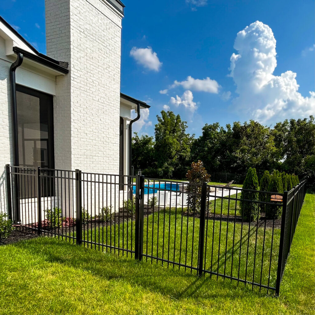 A black aluminum fence installed around a residential property with a swimming pool in the background by Pro Fence in Decatur, AL