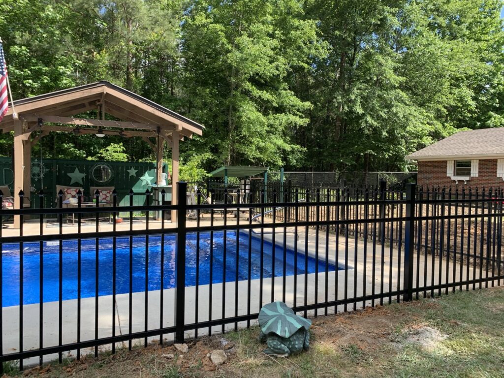 A black aluminum fence installed around a swimming pool at a residential property by Pride Fence LLC in Overland Park, KS.