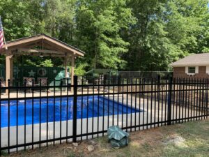 A black aluminum fence installed around a swimming pool at a residential property by Pride Fence LLC in Overland Park, KS.