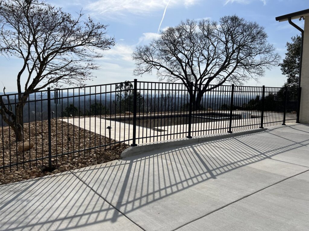 A black aluminum fence enclosing a swimming pool area with a scenic view, installed by Holmes Fence Company in Chattanooga, TN.