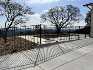 A black aluminum fence enclosing a swimming pool area with a scenic view, installed by Holmes Fence Company in Chattanooga, TN.