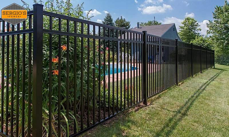 A newly installed black aluminum fence enclosing a pool area by Sergio's Fence in Kansas City, KS.