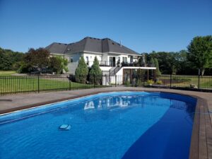 A sleek black aluminum fence surrounding a swimming pool and large home by Top Notch Fence in East Bethel, MN