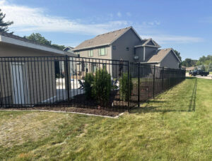 A black aluminum fence enclosing a backyard pool area, expertly installed by Top Rail Fence Des Moines in West Des Moines, IA.
