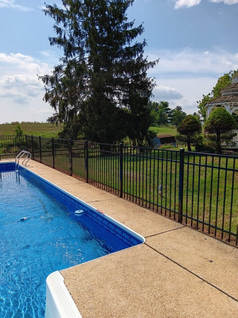 A black aluminum safety fence installed around a swimming pool by A Freedom Fence in Martinsburg, WV.