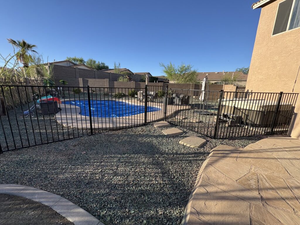 A black aluminum pool safety fence installed around a backyard pool by Fence Company Tucson in Tucson, AZ.