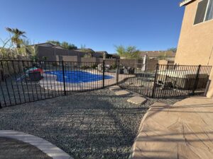 A black aluminum pool safety fence installed around a backyard pool by Fence Company Tucson in Tucson, AZ.