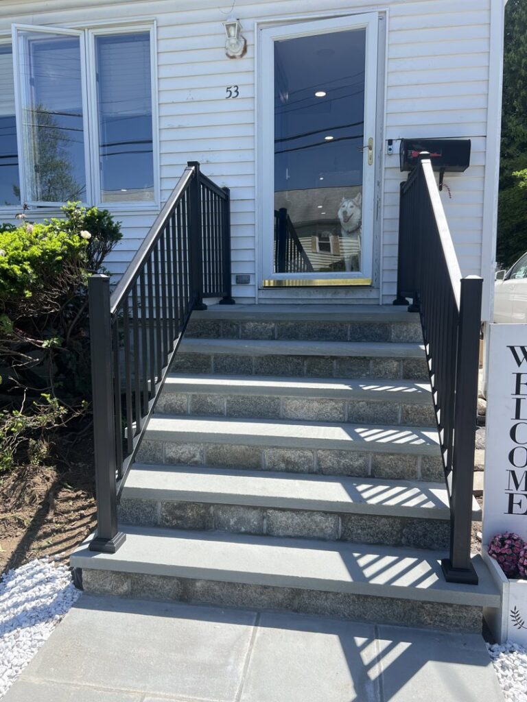 Newly installed black aluminum railings on stone steps leading to a home, provided by AVA Fence & Railing LLC in Stamford, CT.