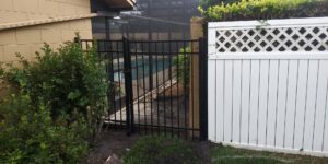 A combination of black aluminum and white vinyl fencing with a gate near a pool enclosure by Florida Professional Fence LLC in Altamonte Springs, FL.