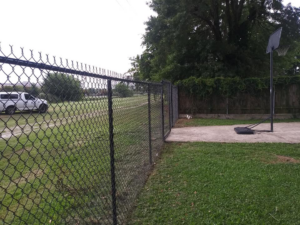 A durable black chain-link fence installed in a residential backyard by Country Boyz fencing in Biloxi, MS.