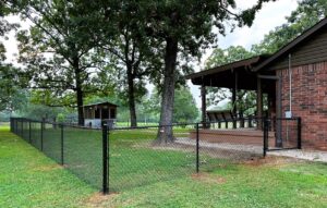 A black chain-link fence enclosing a residential backyard, installed by The Fence Man in Fort Smith, AR