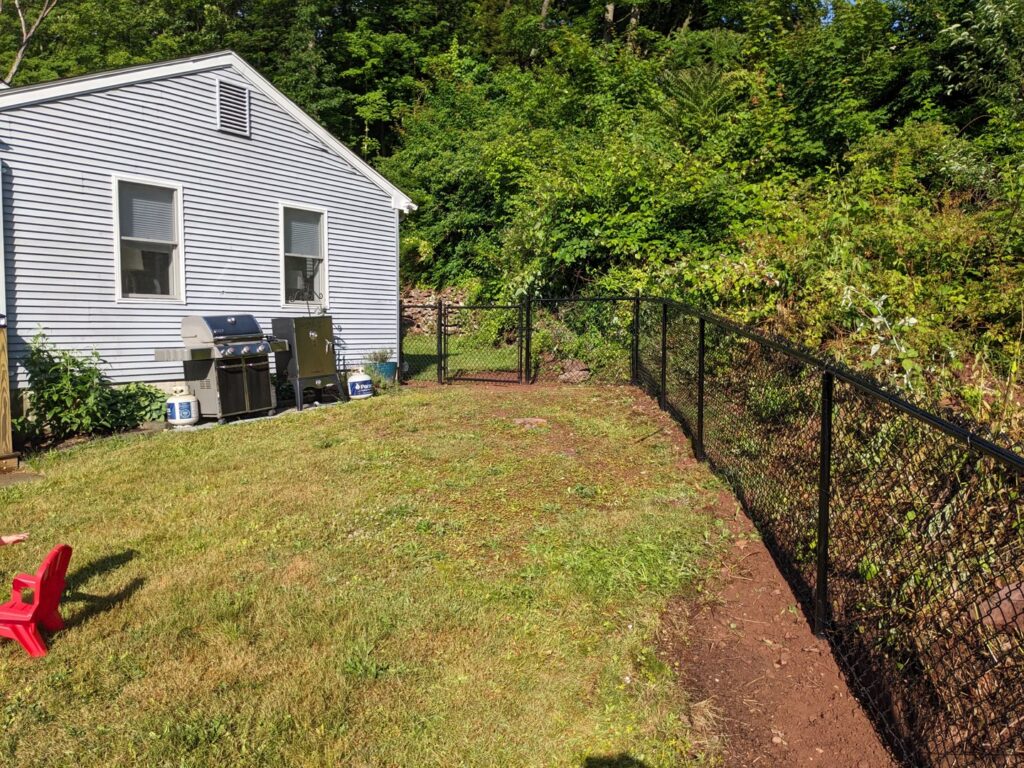 A black chain link fence enclosing a backyard by White Eagle Fence Inc in New Haven, CT.
