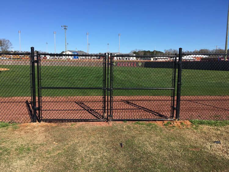 A black chain link fence with a double gate enclosing a baseball field by Precision Fence in Meridian, MS.