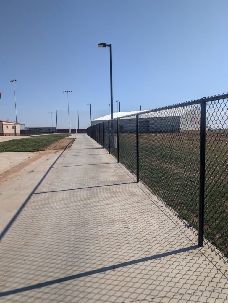 A durable black chain-link fence installed along a pathway by Pro Insulation and Fence in Wichita Falls, TX.