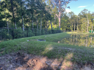 A durable black chain-link fence installed along the edge of a pond by Alabama Fence & Rail LLC in Birmingham, AL.