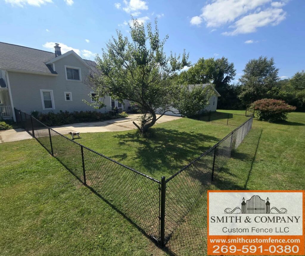 A black chain-link fence installed around a tree in a residential yard by Smith & Company Custom Fence LLC in Niles, MI.