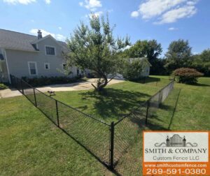 A black chain-link fence installed around a tree in a residential yard by Smith & Company Custom Fence LLC in Niles, MI.