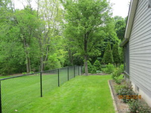 A black chain link fence installed along the perimeter of a residential backyard by Metrofence in Grand Rapids, MI.
