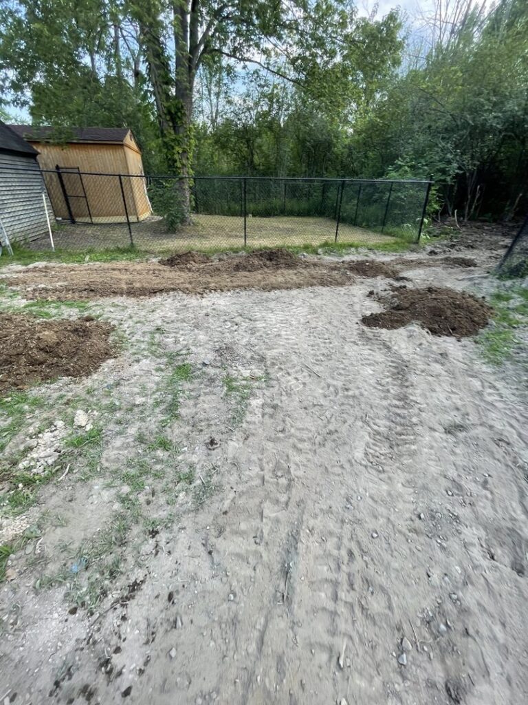 A newly installed black chain-link fence in a backyard with a shed and recently disturbed ground by Vision One Construction in Schenectady, NY