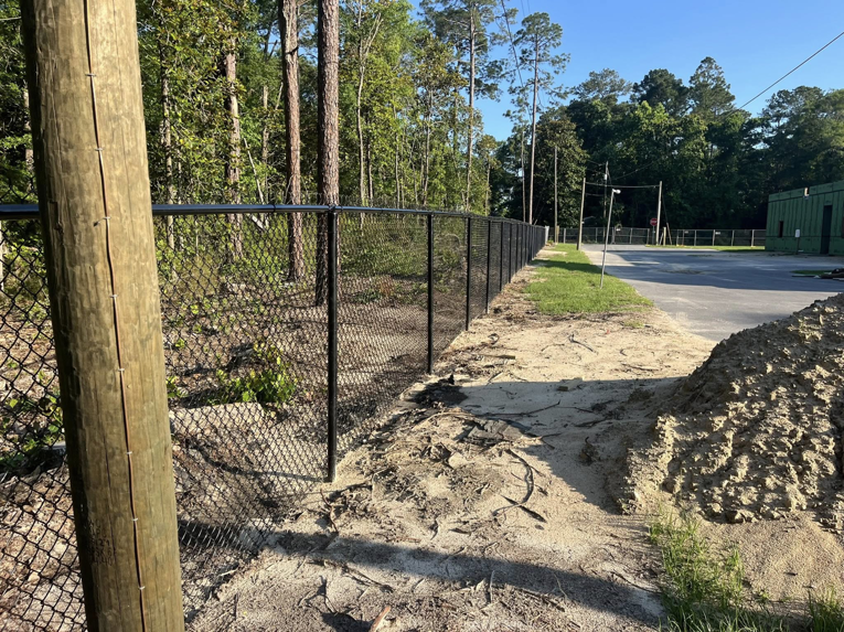A black chain-link fence securing a construction or dirt area, installed by Alabama Fence & Rail LLC in Birmingham, AL.