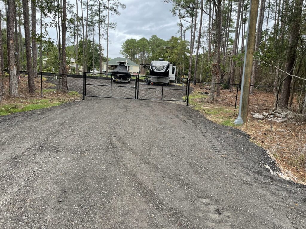 A black chain-link fence with a double gate installed across a gravel driveway by Jaguar Fence LLC in Mobile, AL.