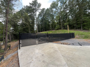 A black chain-link fence with a matching gate installed next to a concrete path by Alabama Fence & Rail LLC in Birmingham, AL.