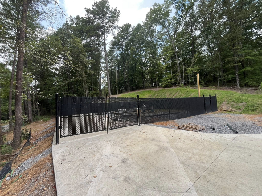 A black chain-link fence with a matching gate installed next to a concrete path by Alabama Fence & Rail LLC in Birmingham, AL.