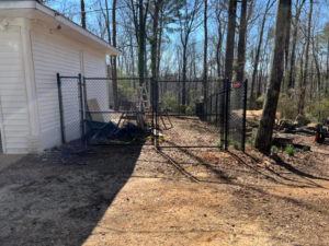 A black chain-link fence with a gate installed next to a residential building by Allen Fences & Decks, LLC in Tuscaloosa, AL.