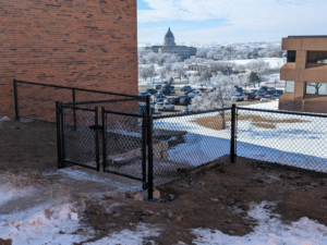 Black chain-link fence with a gate installed on a snowy hillside by Solid Fence Co. in Sioux Falls, SD.