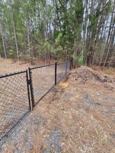 A durable black chain-link fence with a gate installed in a natural setting by Superior Fence & Rail of Charlotte, NC