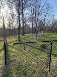 A durable black chain-link fence installed in a spacious grassy area by Petty Fence Company LLC in Evansville, IN.