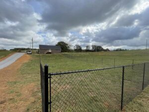 A long black chain-link fence installed across a large grassy property by 865 Fencing in Knoxville, TN.